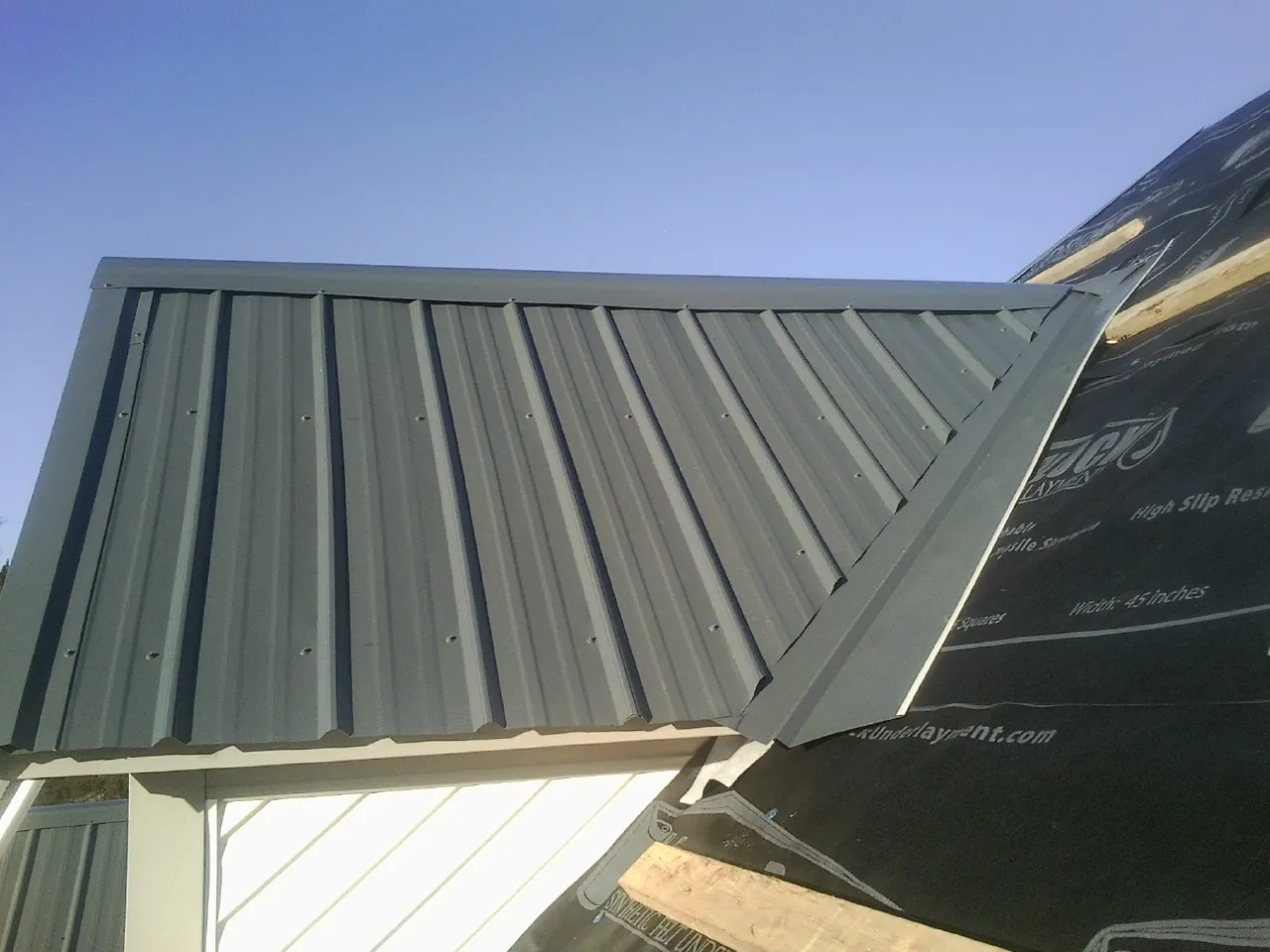 Gray metal roof panels going on over a garage gable in Fort Knox