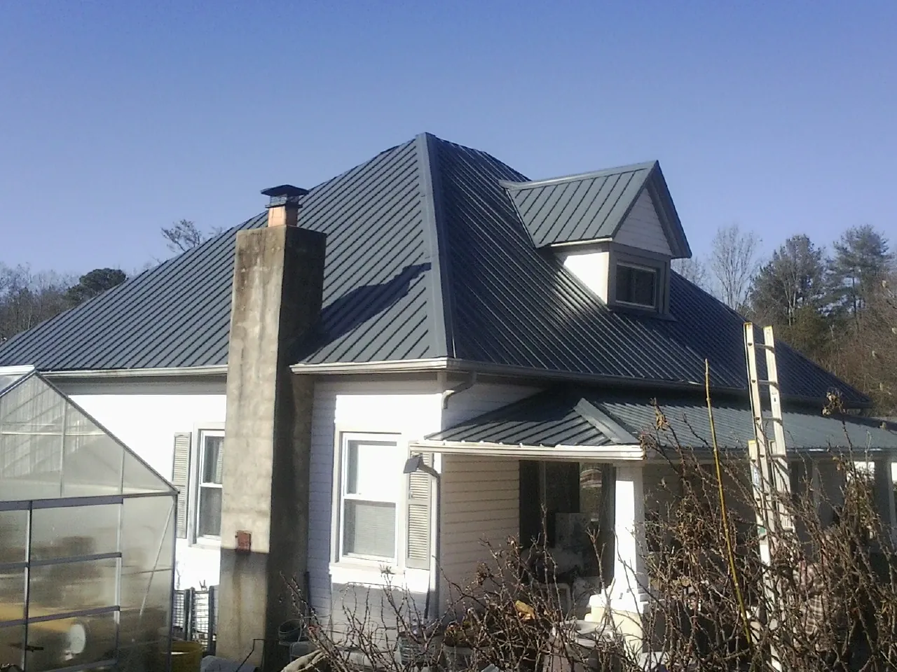 Dark blue standing seam metal roof on a white farmhouse with dormer — Slate & Tile Roof Repair by Roofing Brothers in Fort Knox