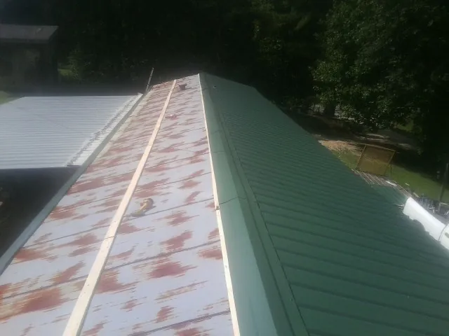 Old rusted panels beside newly installed green metal roofing — Wind Damage Roof Repair by Roofing Brothers in Fort Knox