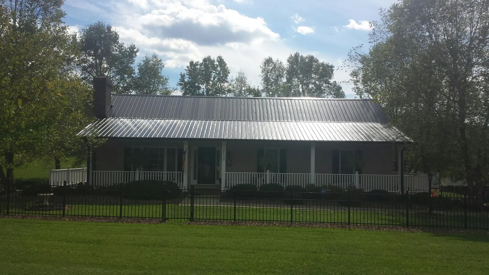 Gray metal roof on a brick ranch with a full width front porch — Gutter Guard Installation work by our crew in Fort Knox