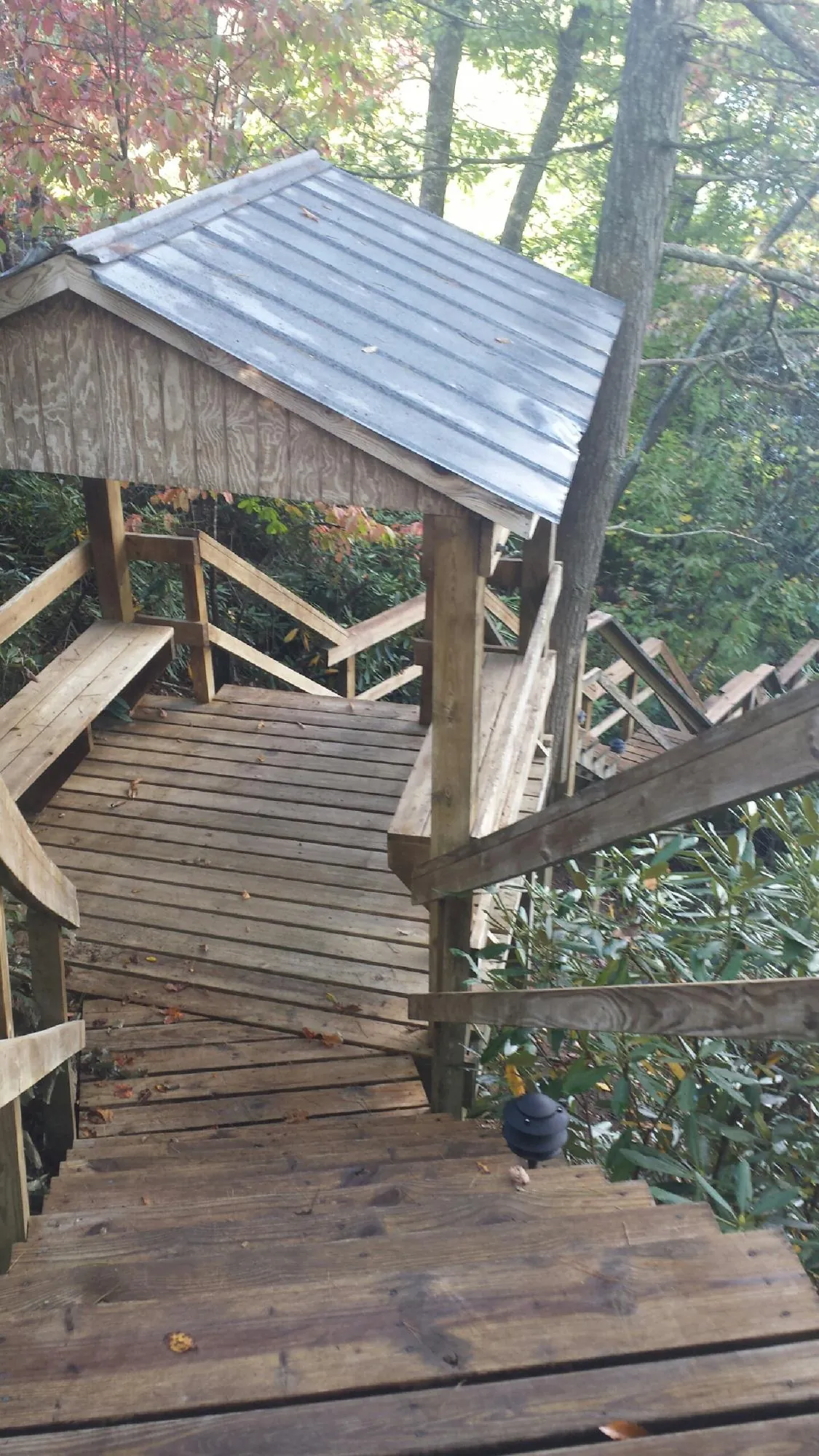 Metal roofed shelter over wooden steps on a wooded walkway — Skylight Repair & Installation work by our crew in Fort Knox
