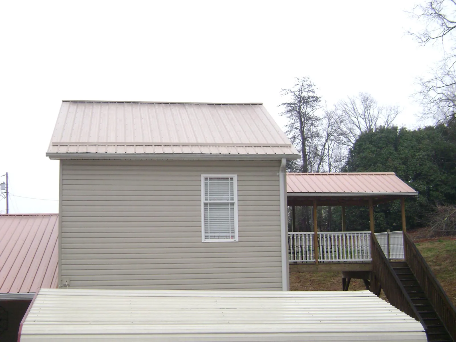 Tan metal roofs on a two story addition and attached porch, from a Roof Replacement job in Fort Knox
