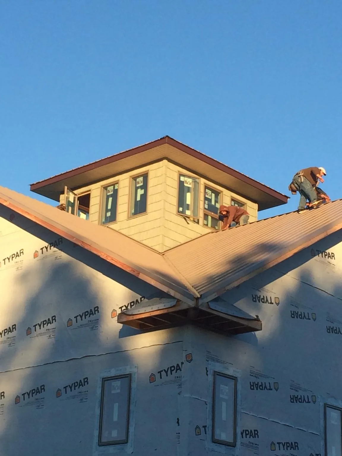 Roofers working around a rooftop cupola on a new metal roof at sunset — Roof Waterproofing in Fort Knox by Roofing Brothers
